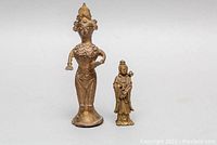 Two bronze Southeast Asian figurines displayed side by side on a white background, showing approximate scale.