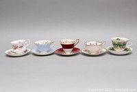 Five bone china teacups and saucers, side view showing patterns and colors