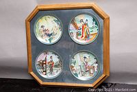 Full view of framed set of four Jingdezhen porcelain plates on dark velvet background in wood frame