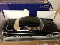 Side view of the black 1955 Chrysler diecast model car showing beige interior and chrome details.