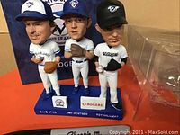 Front view of the set showing the three resin bobbleheads of Dave Stieb, Pat Hentgen, and Roy Halladay on a blue base with their names and Rogers logo.