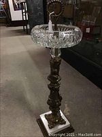 Full view of antique standing ashtray showing cut glass bowl, metal stem, and marble base
