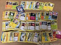 Spread out Pokemon trading cards showing different Pokemon characters, energy cards, and trainer cards in a mix of holographic and standard versions.