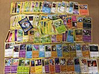 Image shows over 200 Pokémon cards spread out on a flat surface, displaying a variety of Pokémon types and card designs.