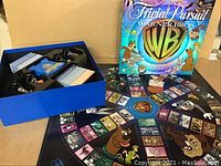 Game box, board, and some cards laid out showing Warner Bros characters and logo
