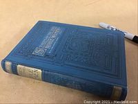 Blue antique hardcover book with embossed decorative border and gold titles on spine.