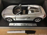 Silver Carrera GT diecast model car displayed in black foam box with Carrera GT nameplate and a Sharpie pen for scale.