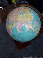 Photo of the vintage globe showing the USSR and Asia region details, mounted on a wooden base with metal frame.