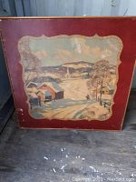 Top view of square antique table showing winter village folk art scene painted on the surface with red border, some scratches visible.