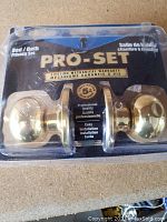 Photo of new Pro-Set privacy lock set sealed in original packaging showing brass finish knobs, warranty details, and product labeling for bed/bath privacy lock.