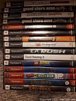Stacked view of 16 PlayStation 2 game spines showing all titles in the lot.