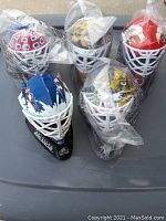Top view of the lot showing five mini goalie masks in plastic bags, each representing different NHL teams.
