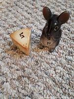 Photo of mouse-shaped ceramic salt shaker and cheese wedge-shaped pepper shaker on carpeted floor.