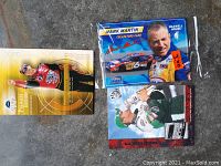 Three racing cards in mint condition; one Mark Martin Maxwell House 2002 card, two Jeff Gordon cards including one Premier Edition and one celebrating a win.