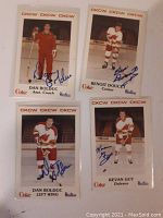 Front view of four autographed Police Hockey trading cards featuring players Dan Bolduc (twice), Benoit Doucet, and Kevan Guy in hockey gear on ice rink background.