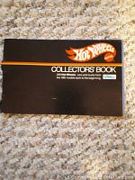 Black cover photo of the Hot Wheels Collector's Book showing logo and title with spine tear noted.