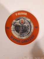 Front view of large orange disc featuring Edmonton Oilers logo, Wayne Gretzky image, 7-Eleven branding, and text.