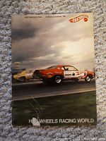 Front cover of the brochure featuring two drag racing muscle cars, one red and white and the other yellow, with a tear near the bottom.