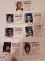 Photo showing seven ESSO hockey cards of Canadian Team players from early 1980s, front side with player portraits and back side with player bios visible.