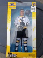 Photo of Mario Lemieux large figure in original box, showing front view of figure dressed in Pittsburgh Penguins uniform with hockey stick and original packaging.