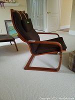 Side view of IKEA POÄNG chair showing wooden frame and padded seat and backrest with small attached cushion.