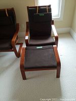 Front view of the brown IKEA Poang chair with padded seat and backrest, paired with matching footstool.