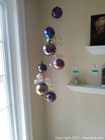Seven hanging glass witch balls arranged vertically against a wall