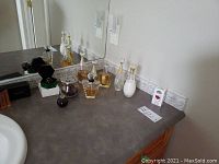 Multiple partial perfume bottles and lotion or liquid soap dispenser on bathroom counter near mirror