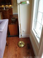 Full view of the metal base floor lamp standing next to a window and couch, showing its height and base size.