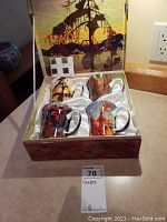 Open box showing 4 ceramic mugs with Tom Thomson prints inside satin lining.