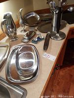 Photo showing large water pitcher, covered butter dish, utensil holder with utensils, and small salt and pepper shakers on countertop
