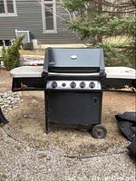 Full front view of black Napoleon propane grill with side shelves and wheels