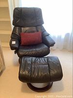 Front view of leather recliner chair and matching ottoman with throw pillow in place