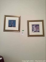 Two signed framed prints by Tang Shao Kuang displayed side by side on wall