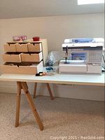 Wide view of sewing machine and organizer box on table with a pair of screwdrivers and notions visible