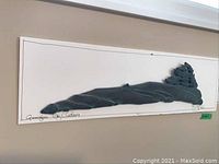 Framed stone art piece with three-dimensional stone sculpture mounted on foam board, showing the overall length and shape.