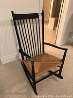 Full front view of black wooden rocking chair on carpeted floor