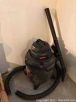 Full view of the Shop Vac with hose and attachment lying on the floor, showing overall condition and size.
