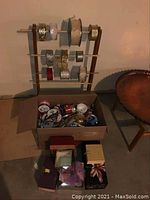 Full view of wood ribbon stand holding several ribbon spools, cardboard box below filled with assorted ribbon spools, and gift boxes arranged nearby.