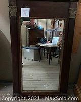 Front view of the large antique wood framed mirror showing full frame and mirror glass with decorative carved elements.