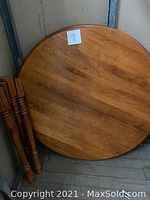 Top view of solid round wooden tabletop with natural wood grain and minor scratches.