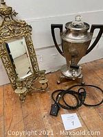 Overview photo of both items side by side showing the samovar with black handles and electric cord and the brass sconce with mirror and candle holders.