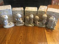 Group of five Precious Moments figurines with matching and unmatched boxes behind them.