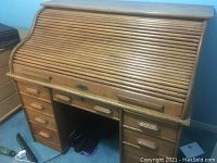 Front view of closed roll-top desk showing overall shape, finish and drawer configuration