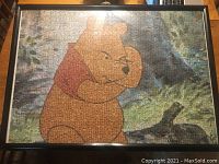 Framed Winnie the Pooh puzzle poster, colorful with forest background, glass-covered black frame, approx 29x21 inches.