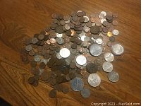 Overview of numerous Canadian and US pennies and various coins on a wooden surface