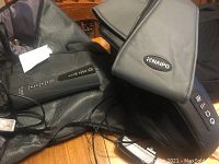 Naipo neck massager device showing control panel, brand name, and electrical cords spread on a wooden surface.