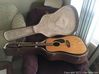 Fender acoustic guitar in an open hard shell case showing the front body with signature.