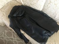 Back view of the Danier black leather coat showing the hood and full length single-piece leather construction with visible stitching and some signs of wear.