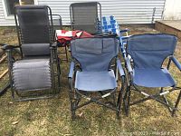 Photo shows seven outdoor chairs on grass including blue fabric camping chairs, woven strap lawn chairs, and reclining black chairs.